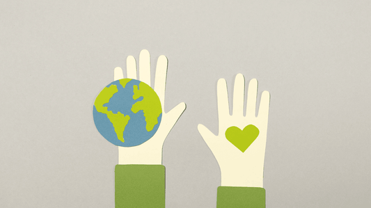 Illustration of two hands: left hand holding a globe and right hand with a green heart symbol on the palm, against a grey background.